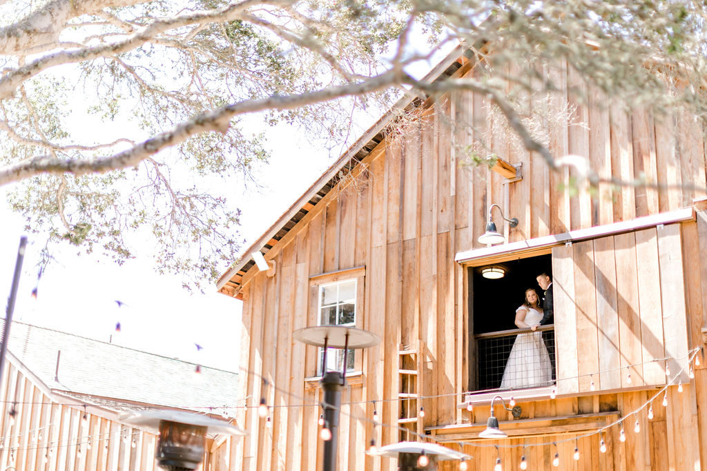 Bride and Groom looking out a barn window 