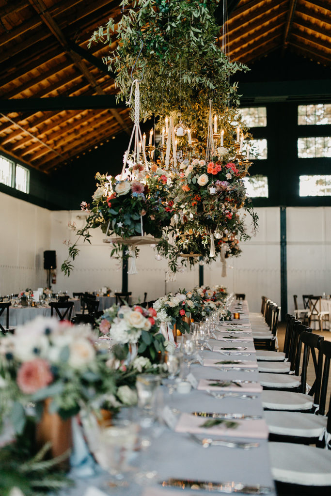 Hanging floral arrangement with brass chandelier over head table