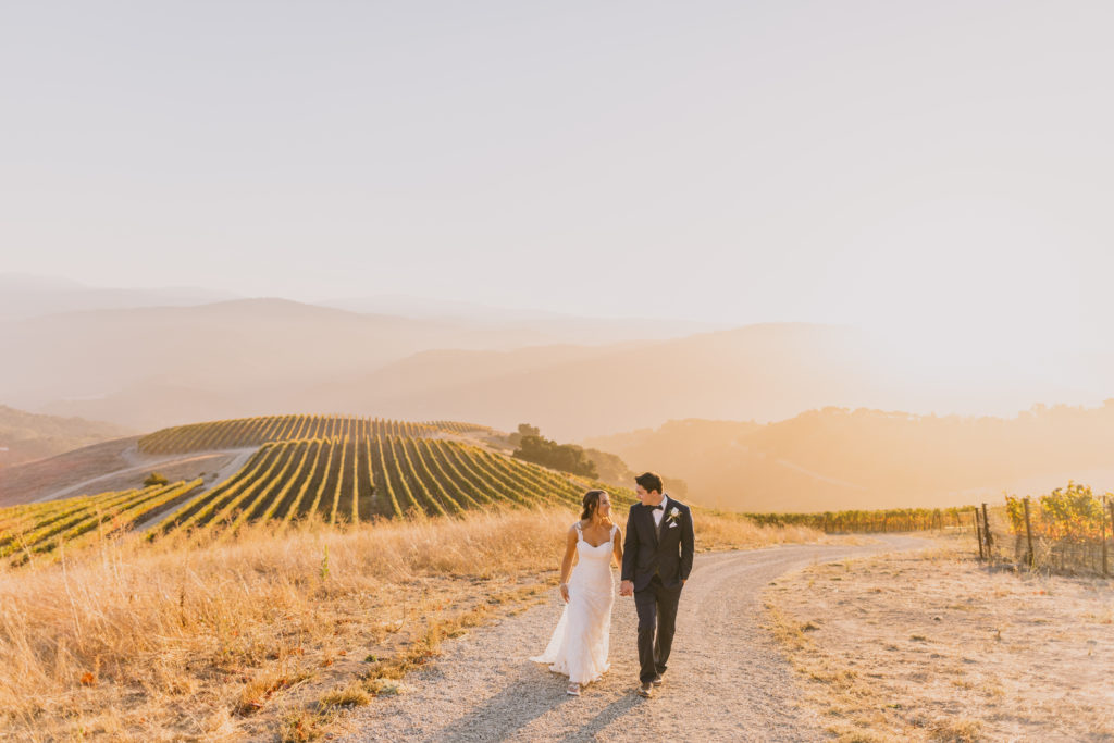 couple walking along hillside of the rolling vineyard