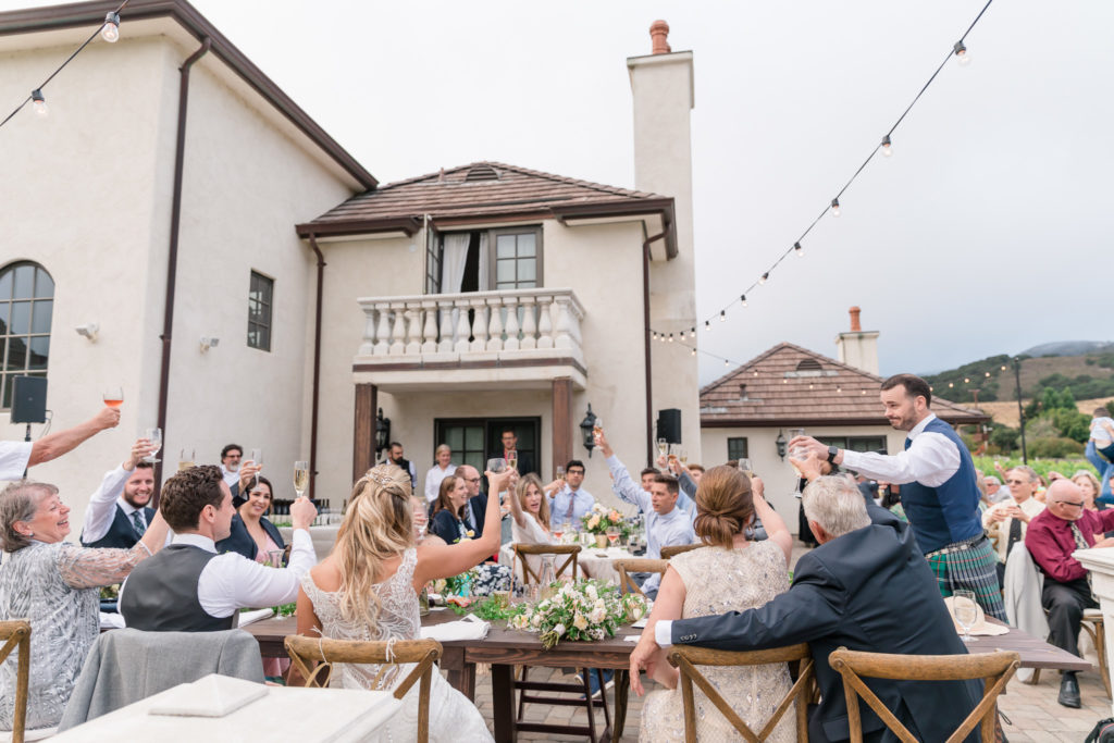 Wedding party toasting at the end of a toast from the best man at a wedding at the Vineyard House in Carmel Valley. 