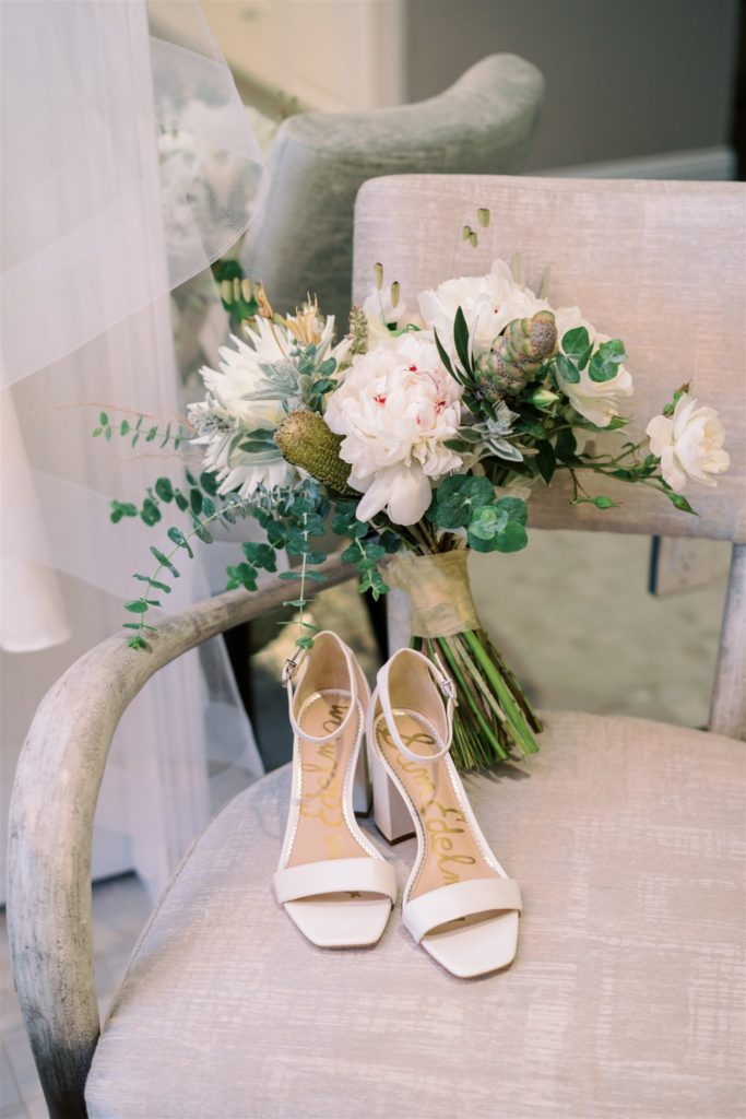 Bouquet of white and green florals on a chair with wedding shoes