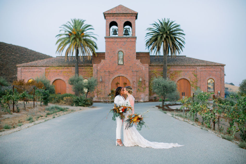 Same sex couple embracing infront of Eden Rift winery Tuscan inspired winery