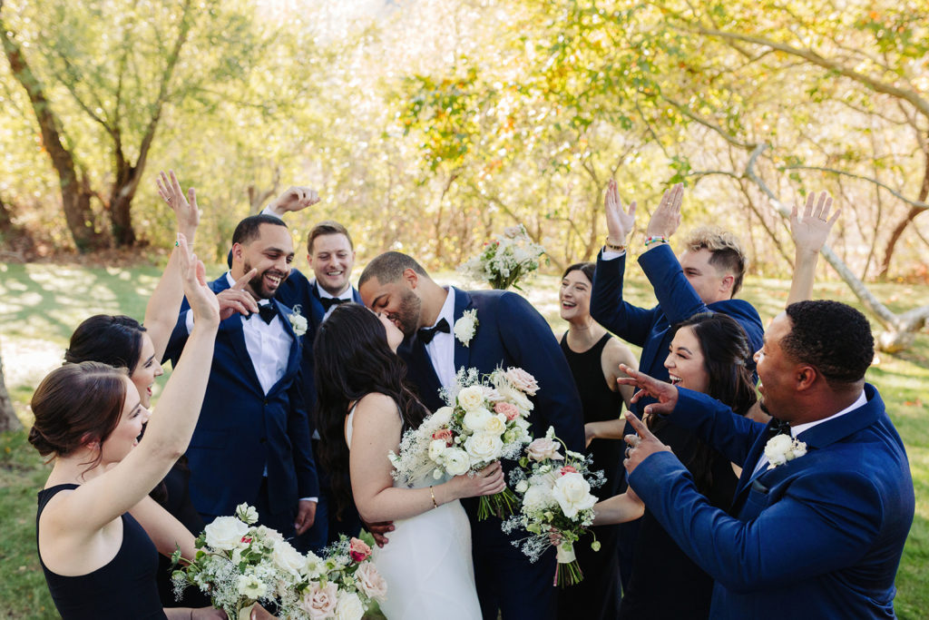 Wedding Party cheering on bride and groom kissing