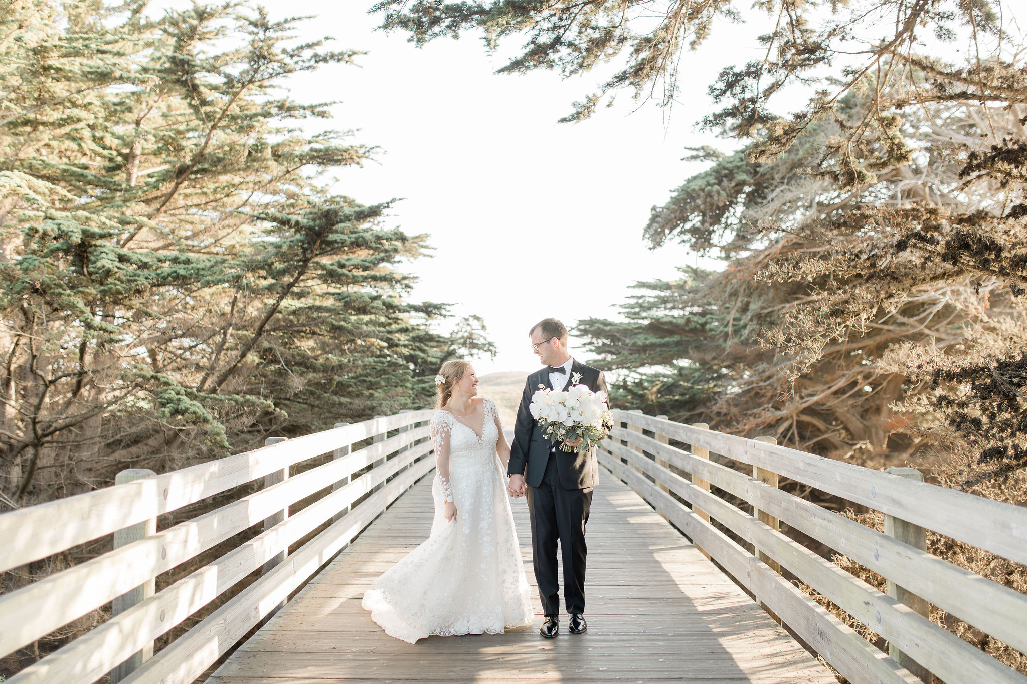 Bride and Groom walking across a bridge