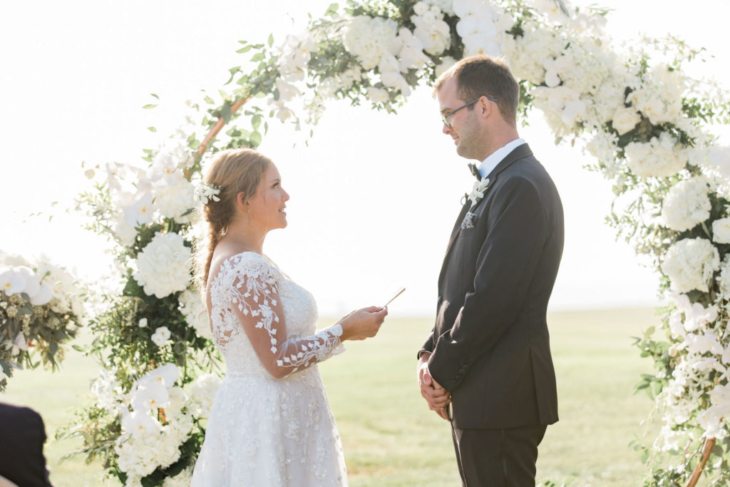 Bride and Groom during the ceremony in front of circle floral arch